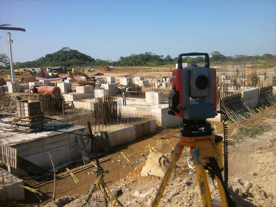 Estación total frente a una obra en construcción