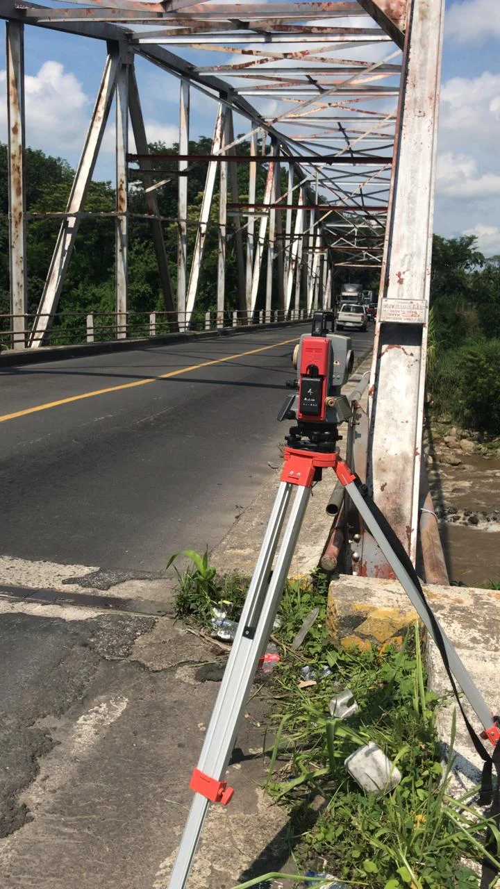 Estación total junto a un puente metálico
